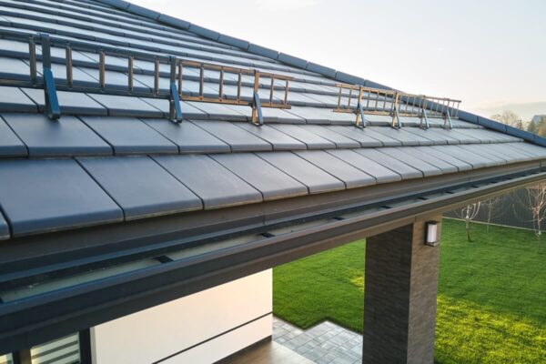 Dach pokryty szarymi płytkami z widocznymi akcesoriami dachowymi.