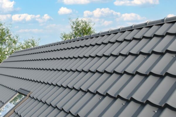 Na zdjęciu widać blachy dachowe na tle nieba i zieleni.